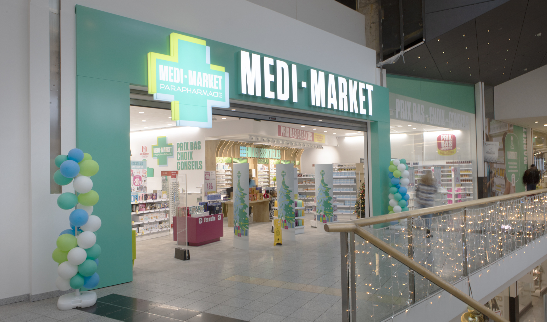 Façade de la parapharmacie Medi-Market avec enseigne lumineuse verte et blanche, décorée de ballons bleus, verts et blancs.